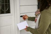 a woman bringing an envelope to a neighbor 