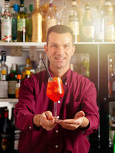 Smiling male bartender offering a freshly made cocktail in a modern bar setting