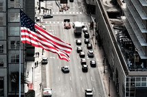 American flag over a city street 