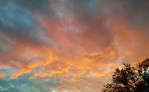A beautiful fall sunset adorns the sky with orange, yellow, purple gray and blue colors just before setting for the day. The cool weather brings some beautiful sunsets during the fall season that light the sky and bring multiple layers of colors to enjoy along with the leaves on the ground and the trees. 