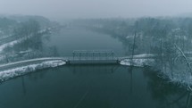 falling snow over a river and bridge 