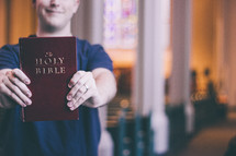Man holding up a Bible in a church 
