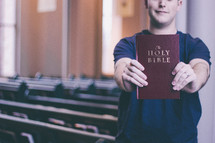 Man holding up a Bible in a church 