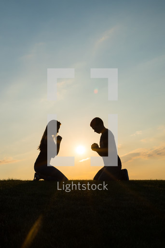 A couple kneeling in prayer together at sunset — Photo — Lightstock