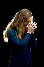 woman with head bowed in prayer and praying hands 