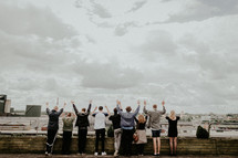 people standing on a rooftop with hands raised 