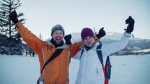 a couple in winter gear with arms raised 