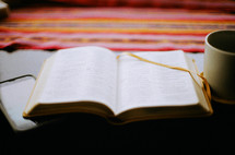 A Bible laid on a table with phone and coffee