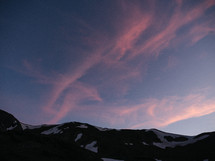 pink clouds over melting snow on a mountain 