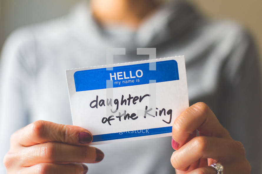 woman holding a name tag with the word daughter of the king 
