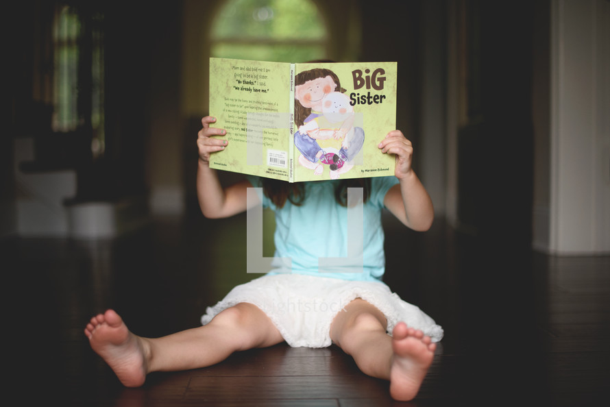 a girl child reading a big sister book 
