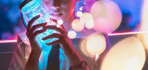 a young girl holding a mason jar full of fairy lights 