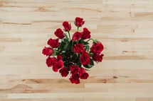 Red roses on a wooden table from above.