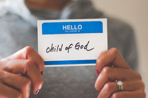 woman holding a name tag with the word child of God 