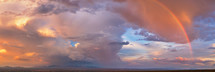 Dramatic panorama of storm clouds and rainbow over the desert. 