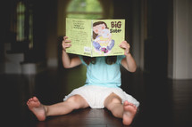 a girl child reading a big sister book 