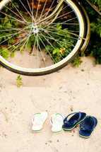 bicycle tire and flip flops in the sand 