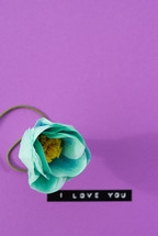"I love you," with a turquoise flower on a purple background.