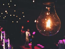 single lightbulb hanging over a band on stage