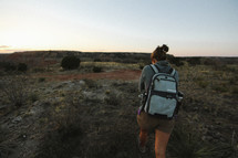 a woman backpacking through a desert landscape 