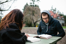 couple reading Bible's together on a picnic table 