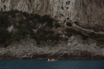 padding a boat along a shoreline in Italy 