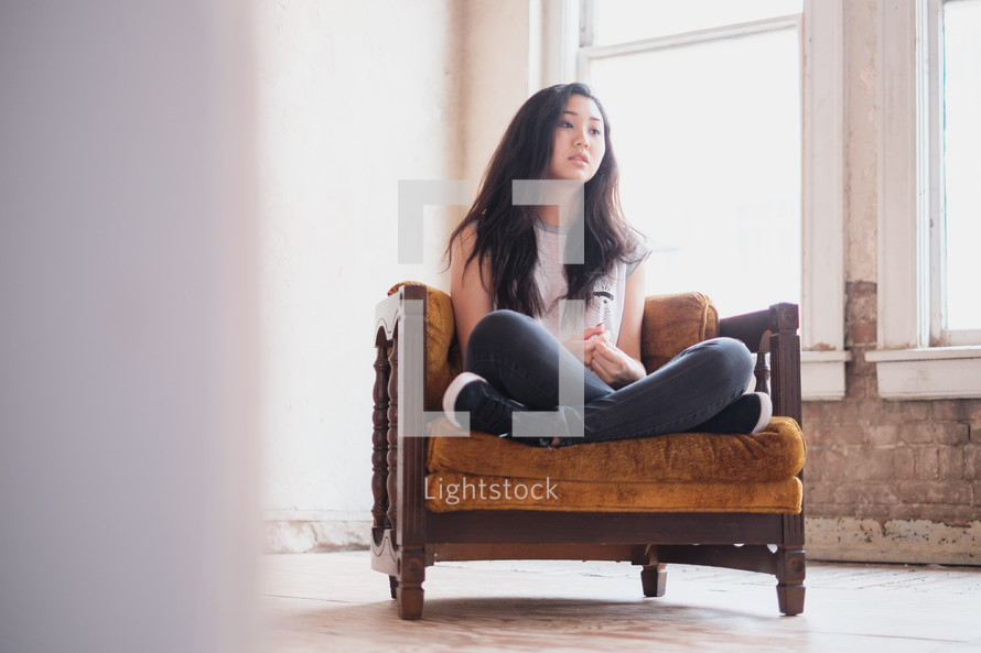 young woman sitting in a chair thinking 