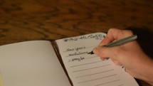 woman writing her New Year's resolutions down