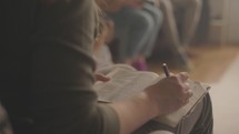 Woman picking up a pen and underlining in her Bible.