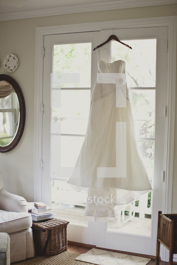 A wedding dress hanging in a window