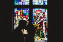 The silhouette of a man and woman kissing in front of a stained glass window