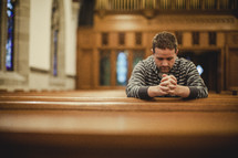 Man sitting in empty church pew praying