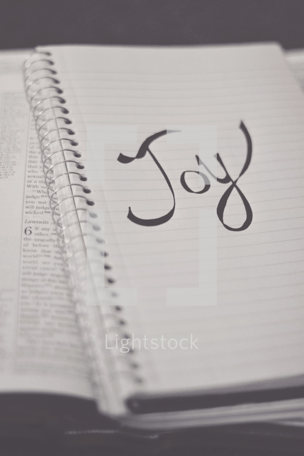word Joy on a notebook on the pages of a Bible 