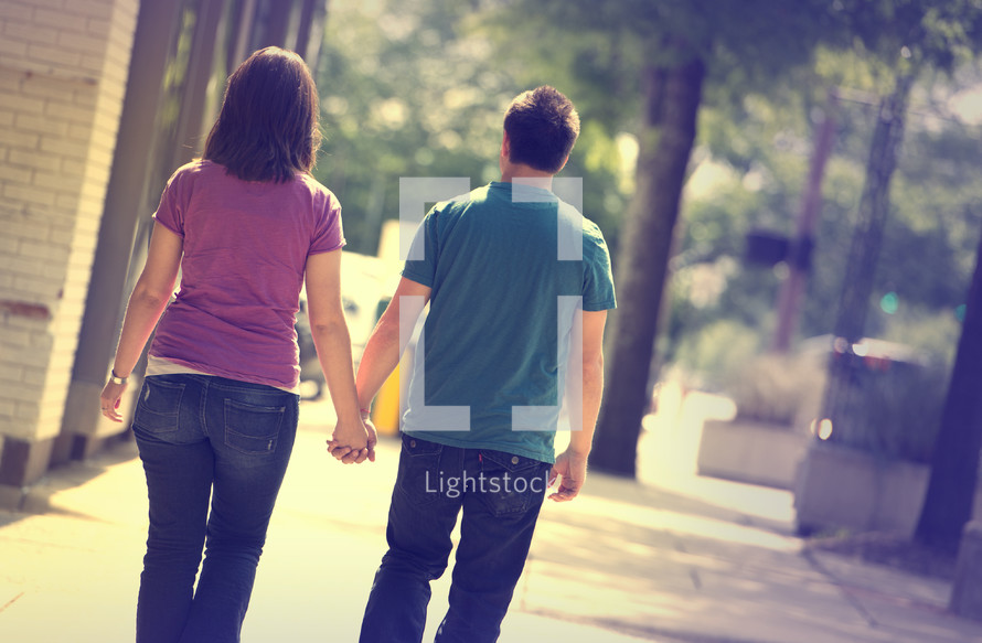 man and woman walking on a sidewalk holding hands