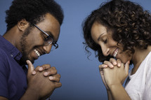 a couple with bowed heads praying together 