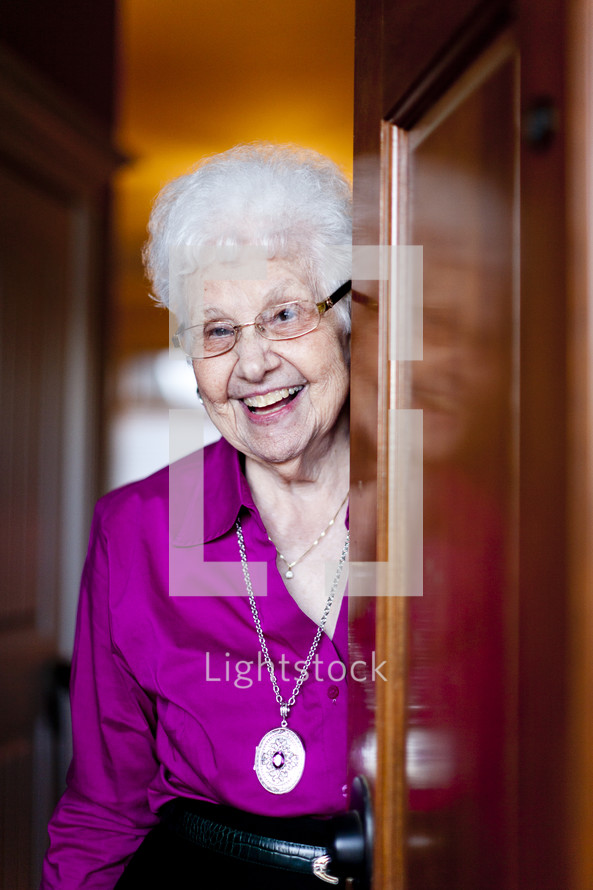 woman smiling from behind a door