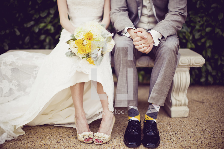 A bride and groom sit on a bench after their wedding