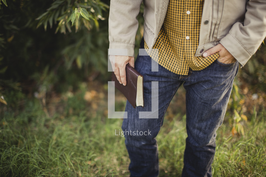 torso of a man holding a Bible