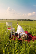 a woman relaxing lying on a blanket in the grass