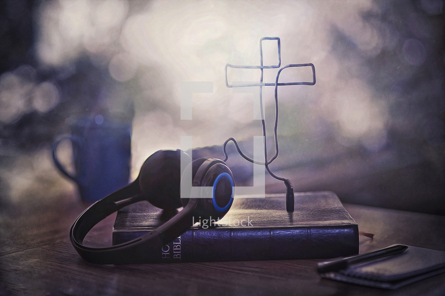 headphone cords in the shape of a cross on a Bible 