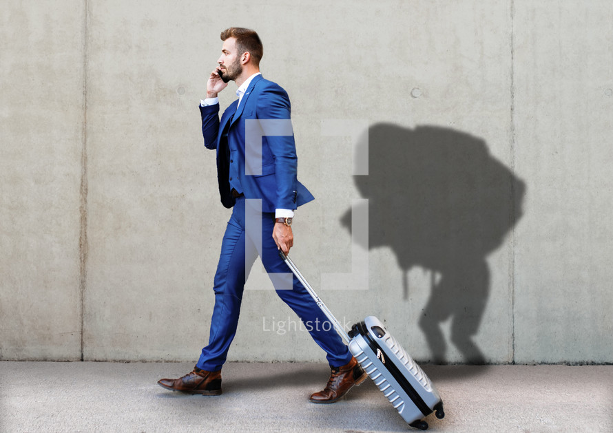 Business man walking with suitcase with shadow of a man burdened by baggage
