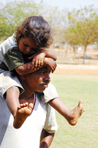 girl child riding on father's shoulders 