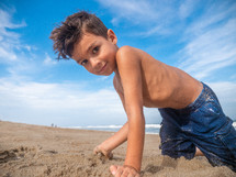 a boy playing with sand on a beach 