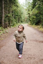 toddler walking on a dirt road 