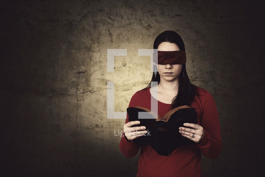 A blind folded woman reading a Bible. 