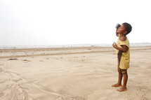 child standing barefoot on desert sand 