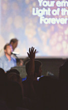 Silhouette of audience with hands raised at a Christian conference.