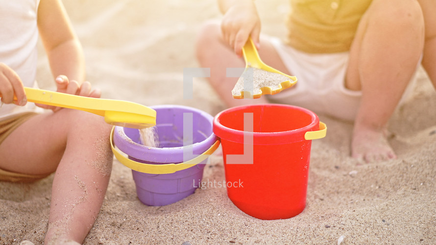 Unrecognizable babies playing on beach in sand with plastic toys. Summer sunny day. Children, family, toddler boy concept. High quality photo