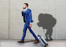 Business man walking with suitcase with shadow of a man burdened by baggage