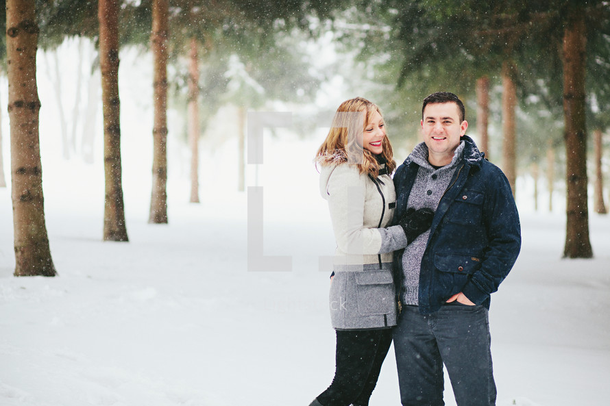 happy couple standing in snow 